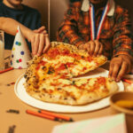 a pizza on a plate and a birthday hat